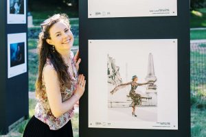 professional photographer Paige Gribb posing next to her work at the Été des Portraits outdoor exhibition in 2021