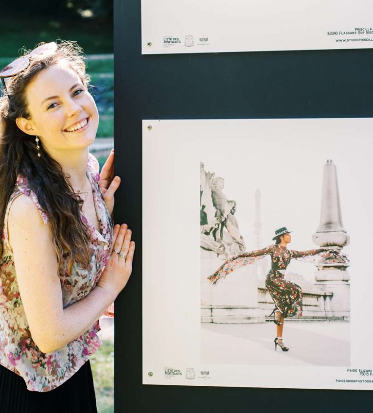 professional photographer Paige Gribb posing next to her work at the Été des Portraits outdoor exhibition in 2021