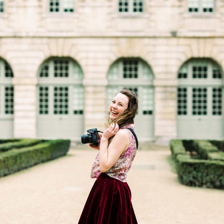 Paige Gribb, a female photographer in Paris, holding a DSLR camera in Paris, France